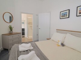 Un dormitorio con una cama, un aparador, un espejo y una puerta que da a un baño.