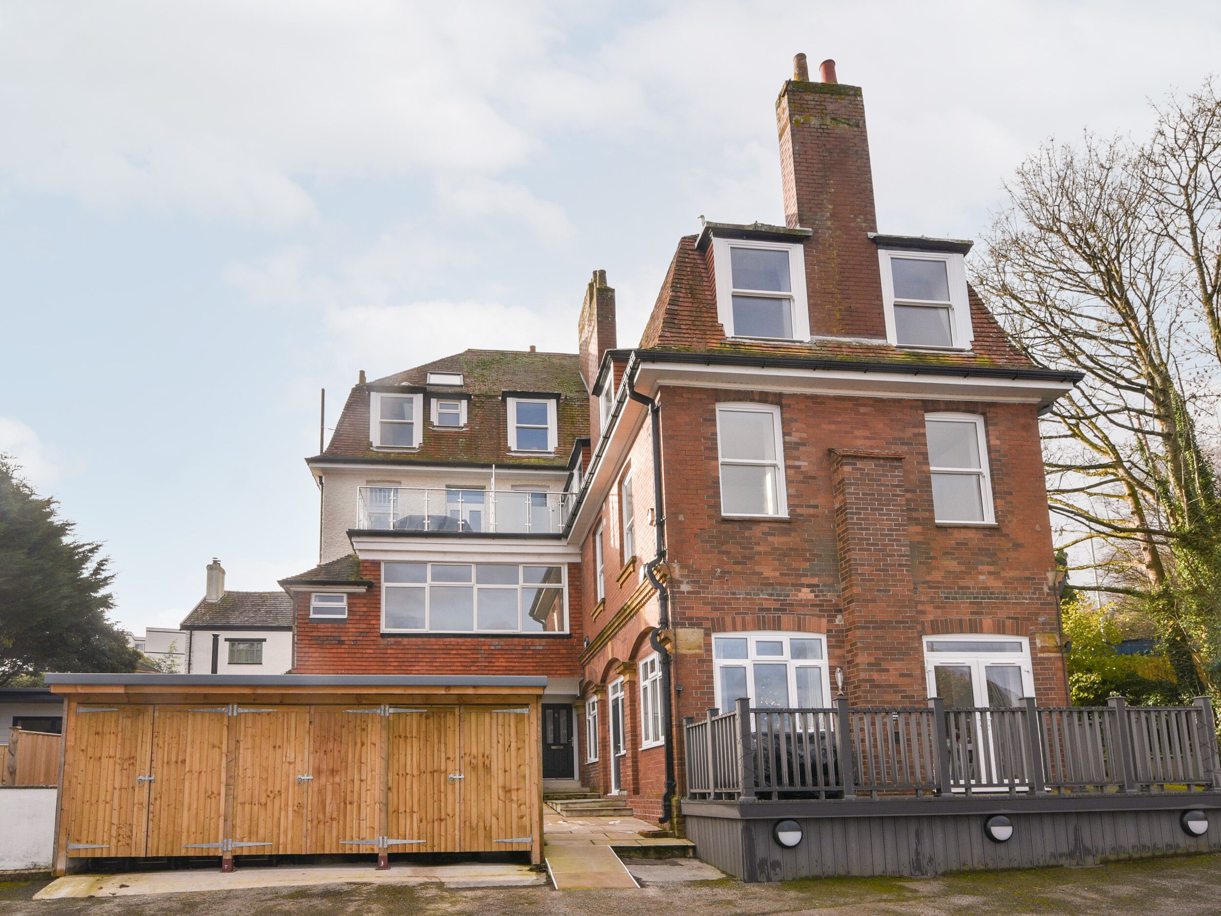 A two-story brick house with a wooden garage and a fenced deck.