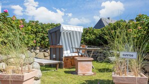 A garden with outdoor furniture, a sign labeled 'sunrise', and a stone wall. - Sie Suchen Nach Einem Domizil, Dass Strandnah Gelegen Ist? (Wenningstedt-Braderup (Sylt))