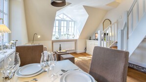 A dining area with a table set for four, a chandelier, and a view of a staircase. - Sie Suchen Nach Einem Domizil, Dass Strandnah Gelegen Ist? (Wenningstedt-Braderup (Sylt))