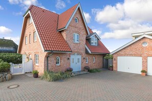 A two-story brick house with a red-tiled roof, a white front door, and a garage. - Strand, Meer & Luxus (Wenningstedt-Braderup (Sylt))