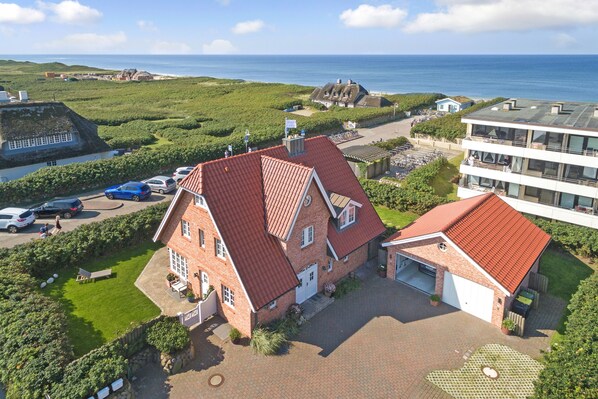 A large brick house with a red roof, a garage, and a well-maintained lawn. - Strand, Meer & Luxus (Wenningstedt-Braderup (Sylt))