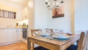 Ein Essbereich mit einem Holztisch, gedeckt für vier Personen, einer Chandelierleuchtre und einer Küche im Hintergrund.