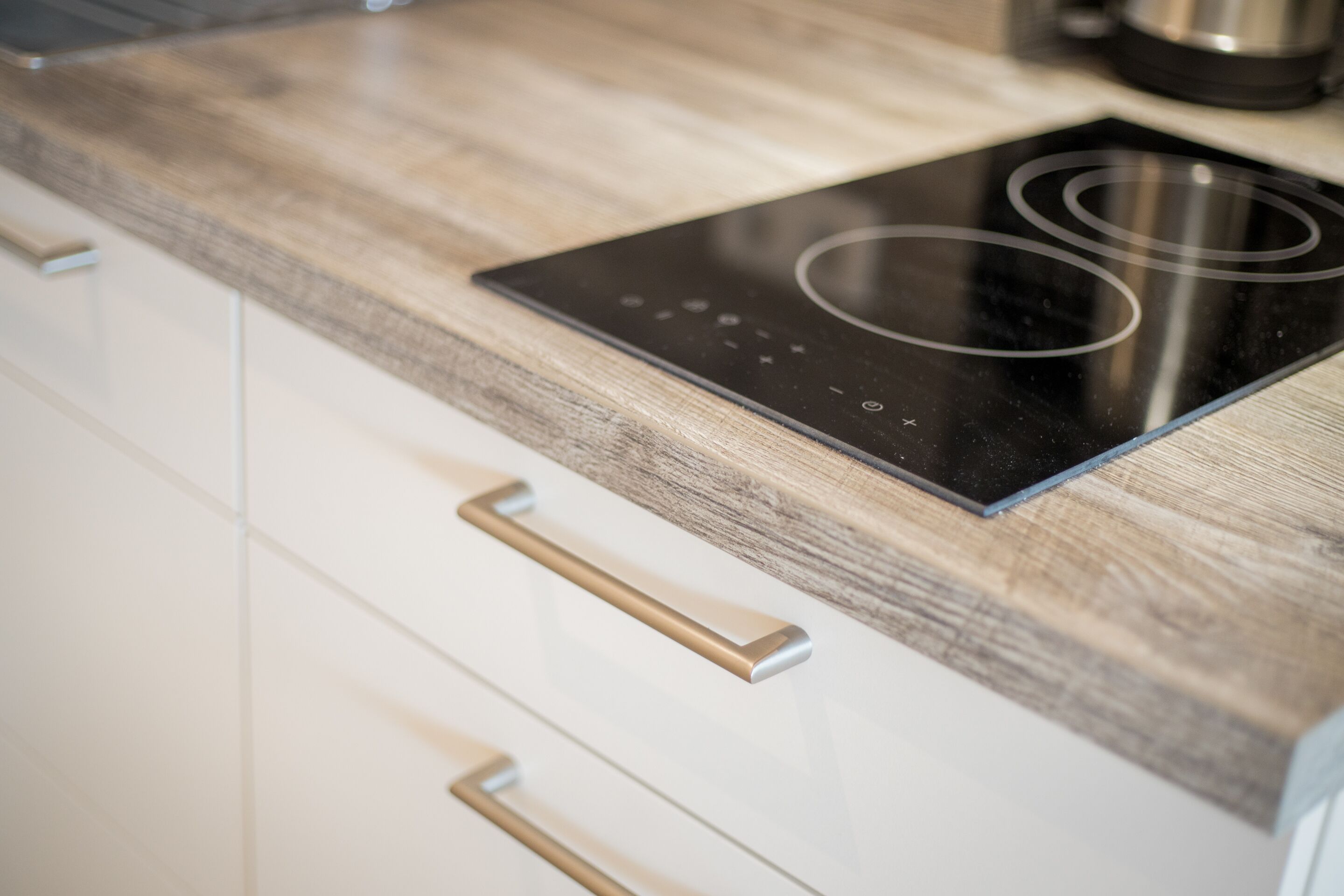 Une cuisine moderne dotée d’une plaque de cuisson à induction élégante et d’un plan de travail en bois.