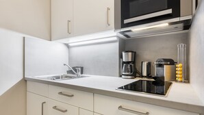 A modern kitchen with a built-in microwave, coffee maker, and a kettle. - Design Kleinod für Preisbewusste, in Bester, Zentraler Lage (Wenningstedt-Braderup (Sylt))