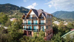 A multi-story wooden building with balconies, surrounded by trees and mountains. - Hotel ANNA PALACE (Khulo)