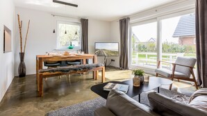 Ein modernes Wohnzimmer mit Holzesstisch, einer Couch und einem Fernseher.
