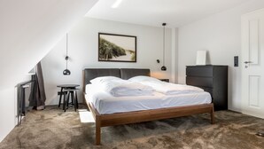 Ein Schlafzimmer mit einem hölzernen Bett, einem kleinen Tisch, einem Stuhl, einem Schreibtisch und einem Kleiderschrank.
