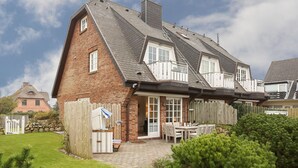 A two-story house with a brick exterior, a sloped roof, and a balcony. - Sylt. Heide. Und Meer (Wenningstedt-Braderup (Sylt))