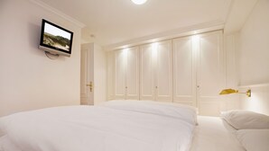 A bedroom with a large bed, a television mounted on the wall, and a wardrobe with multiple doors. - Sylt. Heide. Und Meer (Wenningstedt-Braderup (Sylt))