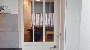 Eine weiße Tür mit Glasfenster, ein kleiner Schreibtisch mit Schubladen und ein Fliesenboden.