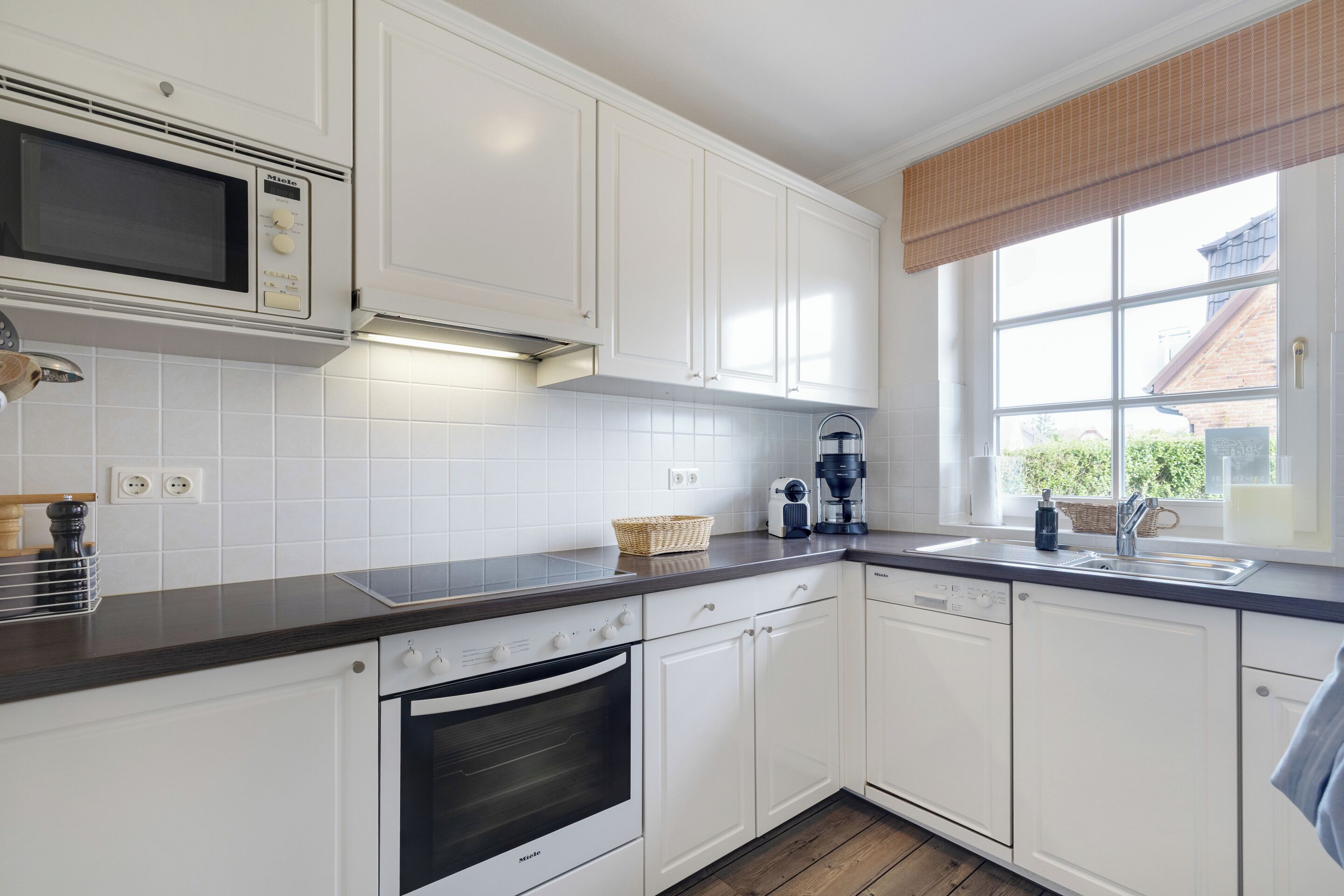 Une cuisine moderne avec des meubles blancs, un four à micro-ondes, un four traditionnel et un lave-vaisselle.