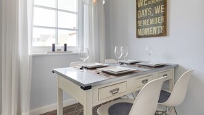 Een eethoek met een tafel gedekt voor twee personen, een hanglamp en een inspirerende quote op de muur.