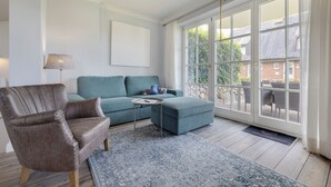 Een woonkamer met een bruine leren fauteuil, een teal bank en een salontafel.
