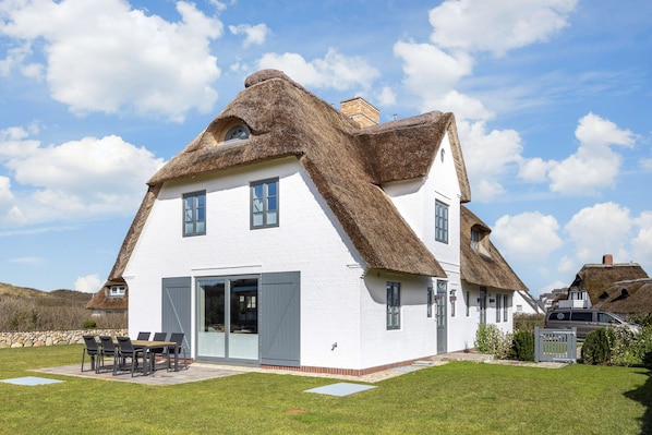 Traditional thatched-roof house with a spacious dining area and a large front door.