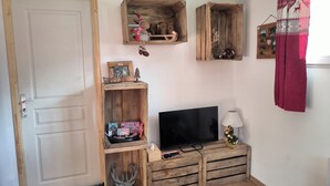 Una habitación con puerta de madera, un televisor sobre un mueble de madera y adornos navideños.
