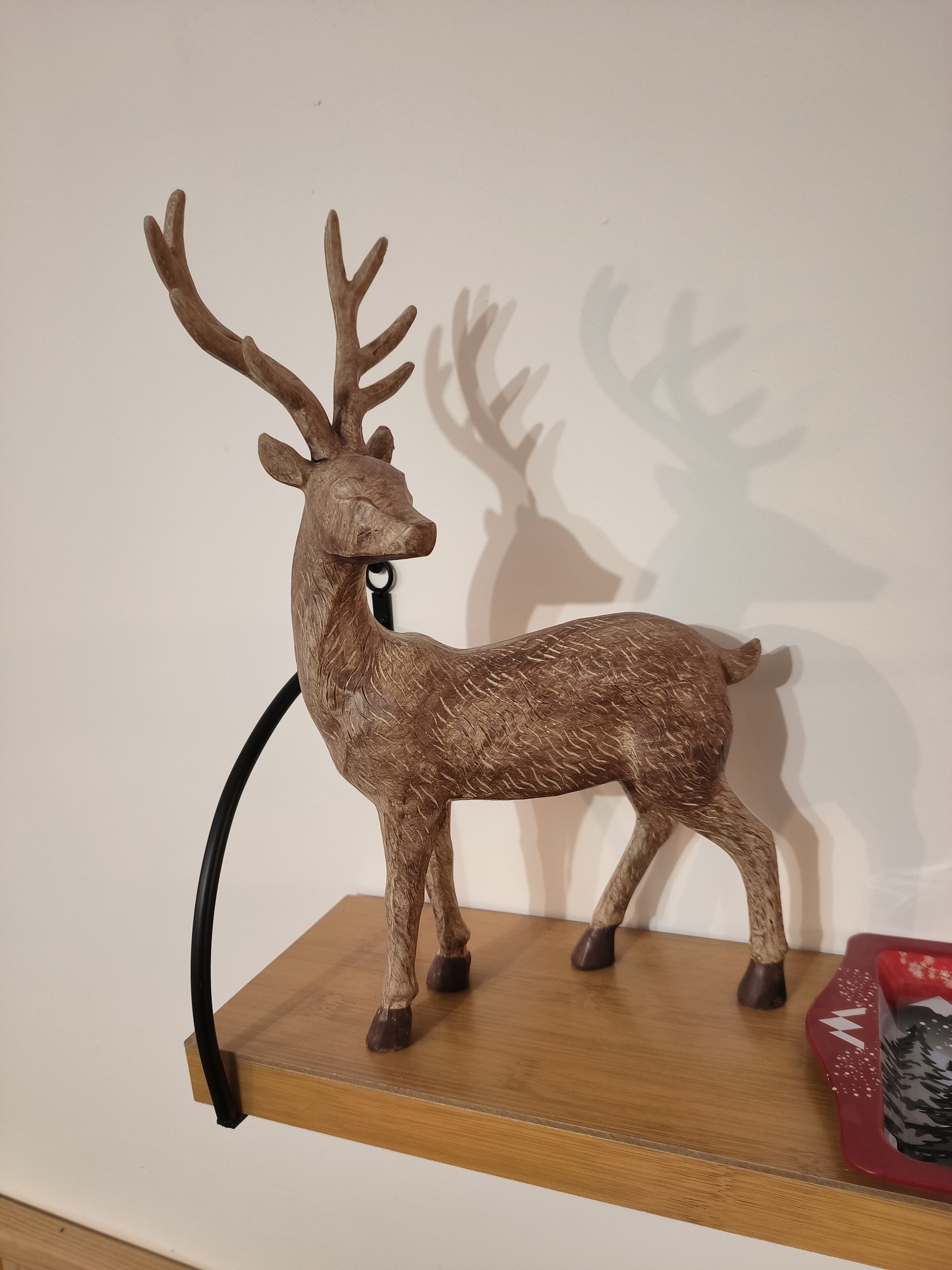 Une étagère en bois ornée d’une figurine de cerf et d’un objet décoratif rouge.