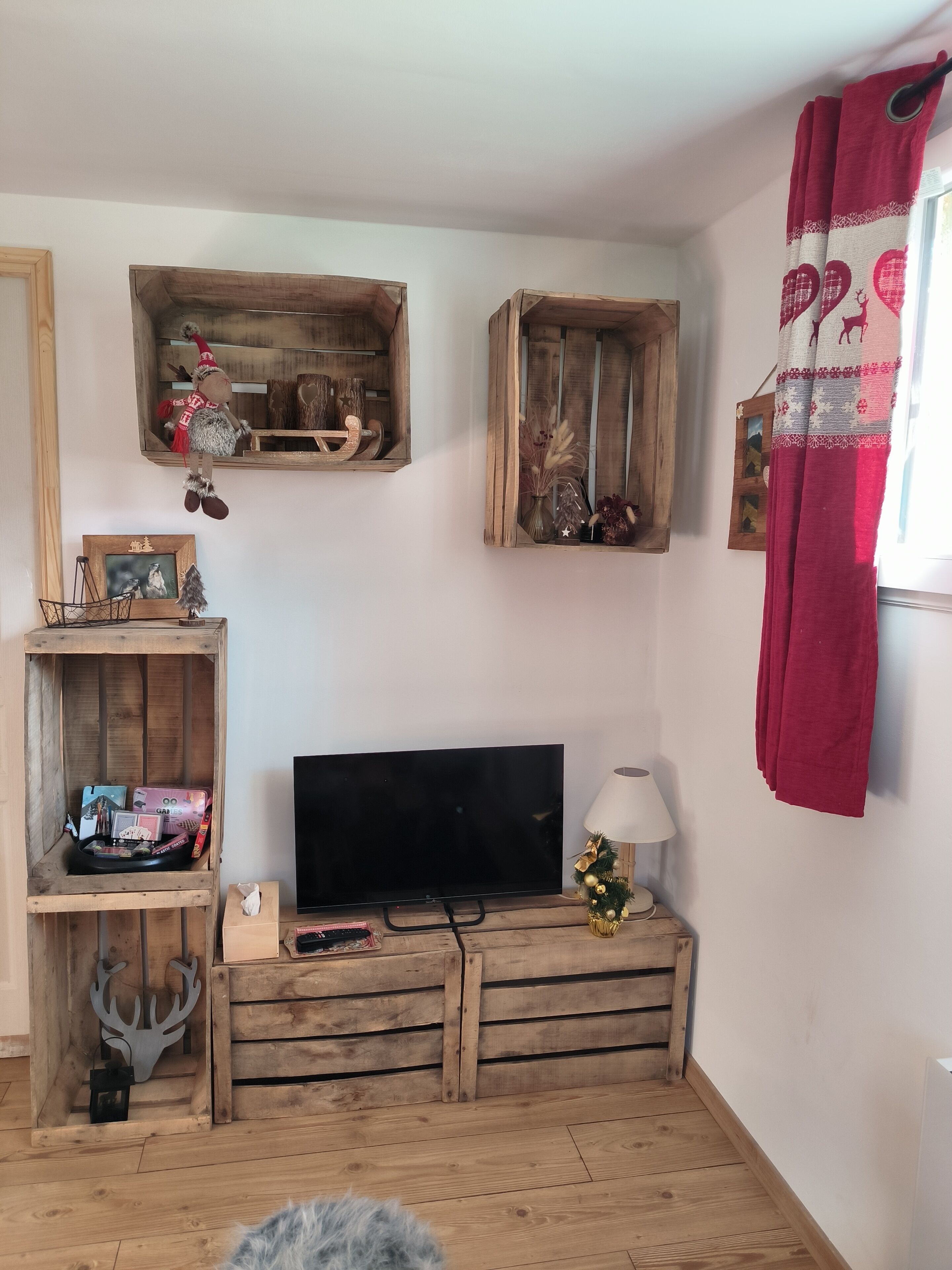 Une pièce au décor rustique, avec un meuble TV en bois, une petite table avec une lampe et des objets décoratifs disposés sur des étagères.
