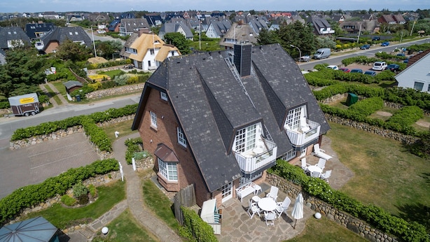 A large house with a spacious patio, a garage, and a driveway. - First-class Suiten in Bestlage (Wenningstedt-Braderup (Sylt))