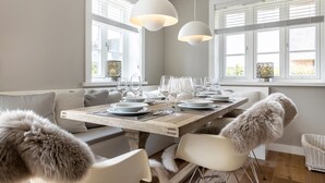 Ein Essbereich mit einem Holztisch, gedeckt für sechs Personen, weißen Stühlen und zwei Pendelleuchten.