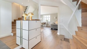 Ein modernes Interieur mit Treppe, einem raumspiegelnden Kleiderschrank und einer Sitzecke.