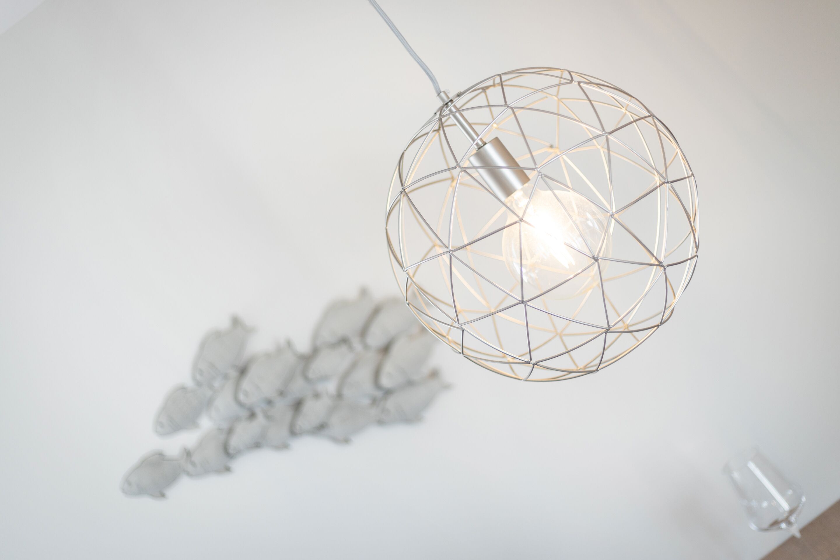 Een bolvormige hanglamp met een geometrisch draadframe.