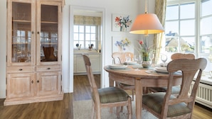 Un coin repas avec un buffet en bois, une table dressée pour quatre personnes et des chaises dotées de coussins à carreaux.