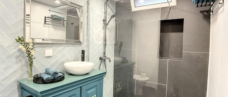 A modern bathroom with a large mirror, a white sink, and a blue cabinet.