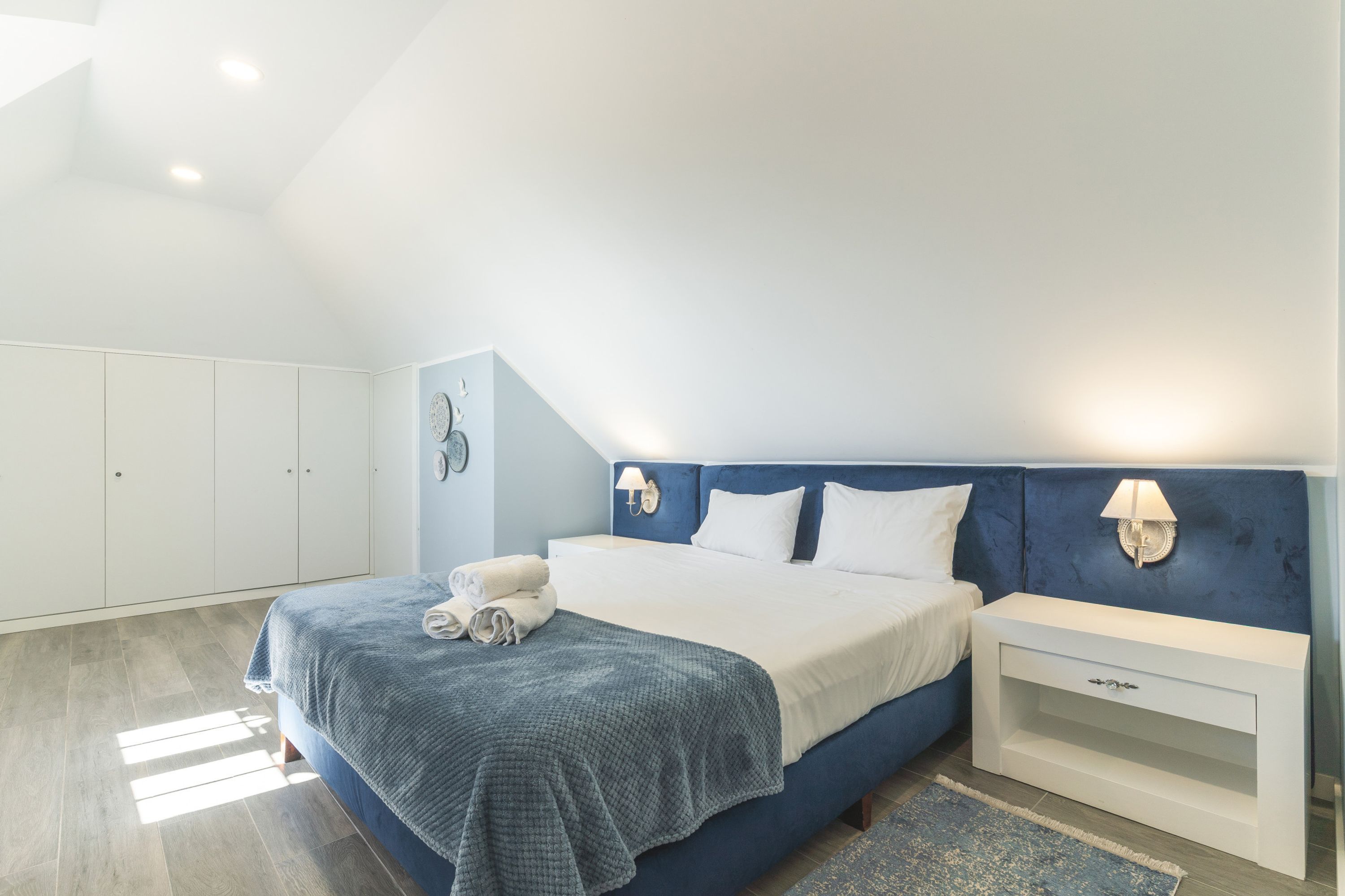 Ein Schlafzimmer mit Bett, Nachttischen, einem Kleiderschrank und einer Deckenleuchte.