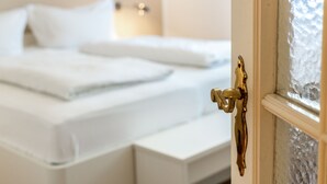Una habitación de hotel con cama, ventana de vidrio esmerilado y pomo de latón.