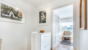 Un pasillo con un armario blanco, una mesa de madera y dos cuadros en la pared.
