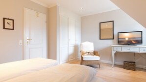 A bedroom with two beds, a desk, a chair, and a television.