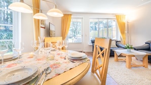 A dining area with a round table set for six, surrounded by chairs. There are three pendant lights above the table. - De-luxe village pond flair. (Wenningstedt-Braderup (Sylt))