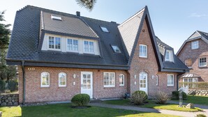 A two-story brick house with a sloped roof, multiple windows, and a well-maintained lawn. - De-luxe village pond flair. (Wenningstedt-Braderup (Sylt))