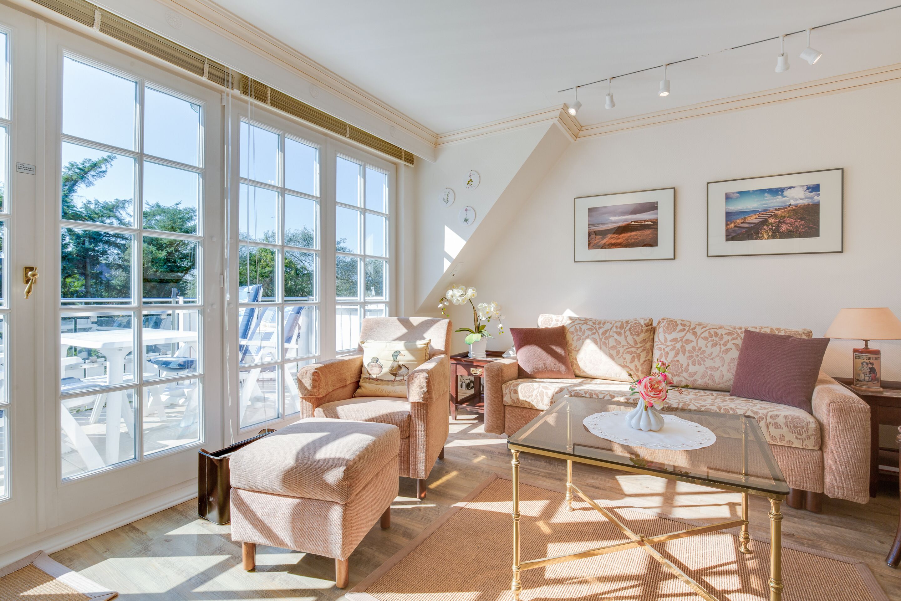 A spacious living room with large windows, a sofa, armchairs, and a coffee table.