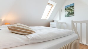 A bedroom with a bed, a window, a nightstand, and a wall-mounted picture. - 2-raum-appartement im OG und DG, ca. 43qm² Nutzfläche für bis zu 2 Personen (Wenningstedt-Braderup (Sylt))