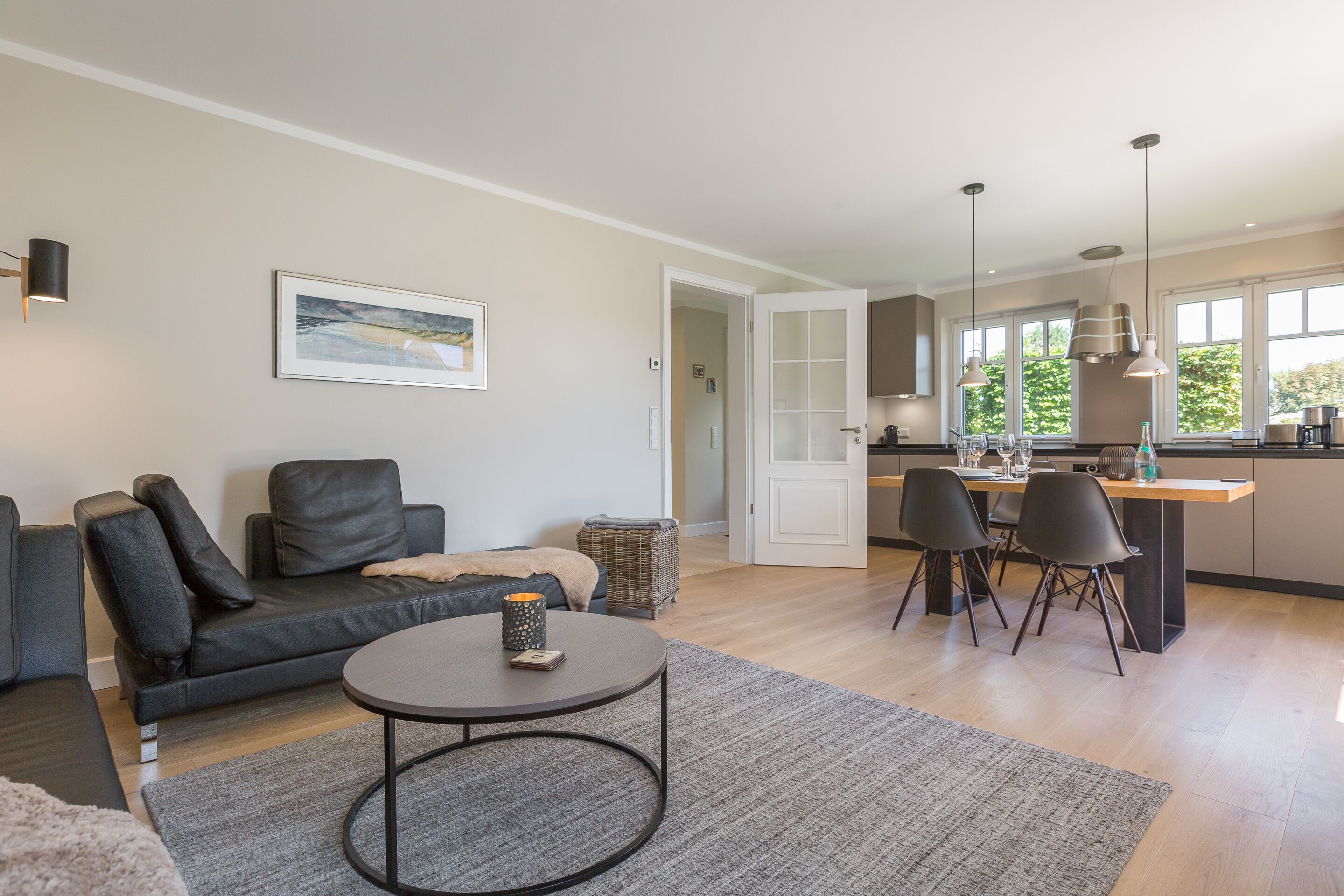 A modern living room with a sofa, a coffee table, and a dining area with chairs and a table.