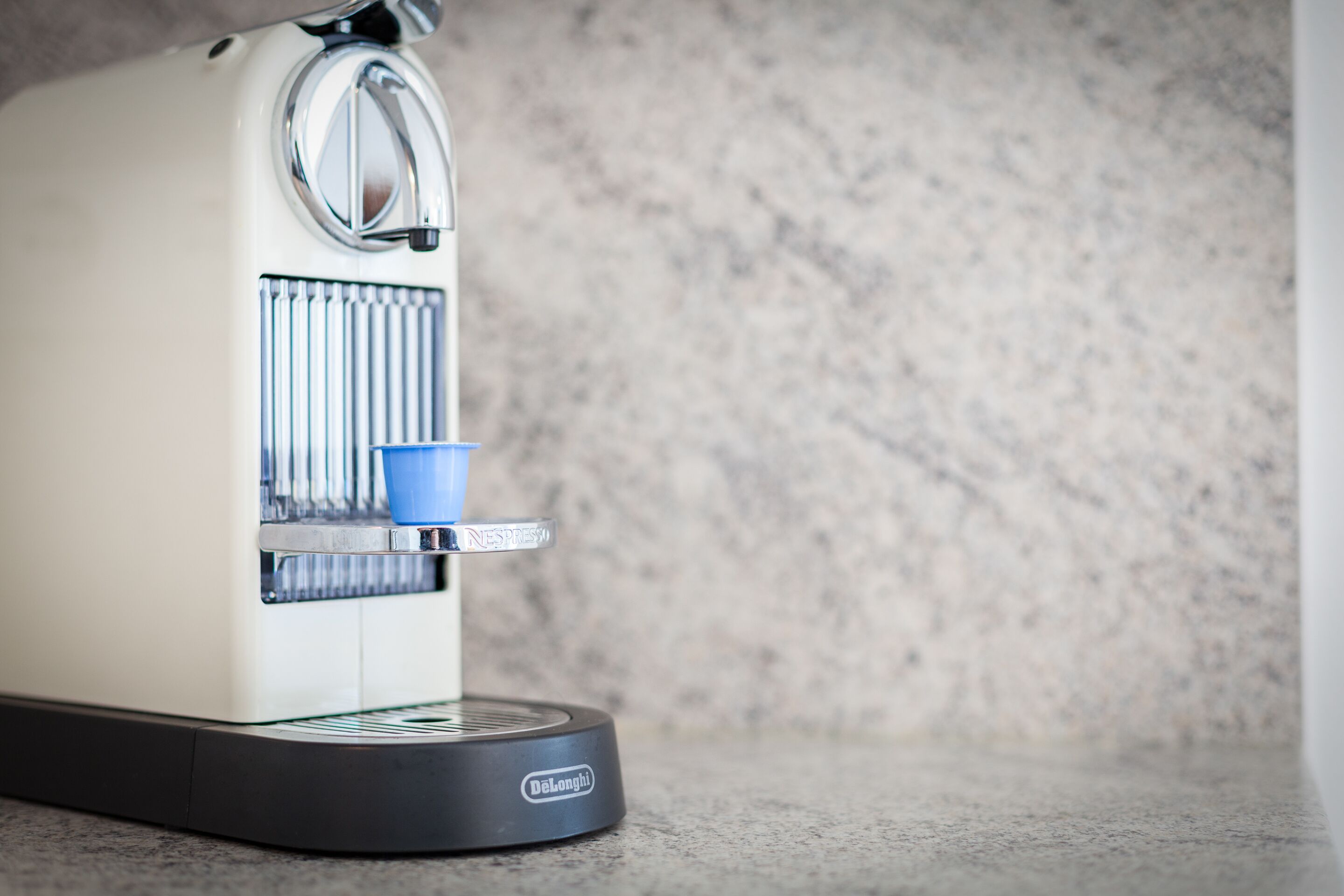 Eine De'Longhi Espressomaschine mit blauem Becherhalter und Wasserbehälter.