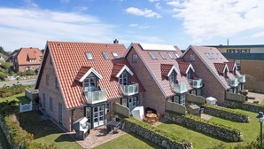 A modern house with a red-tiled roof, multiple balconies, and a well-maintained lawn. - Fantastisch Strandnahe Lage & Beach-style Wohlfühl-atmosphäre (Sylt / OT Westerland)