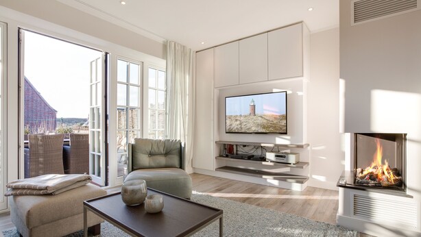 Ein modernes Wohnzimmer mit Kamin, Fernseher und Sofa.