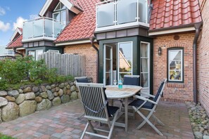 Eine Terrasse mit Tisch und Stühlen, eine Steinmauer und ein Holzzaun.