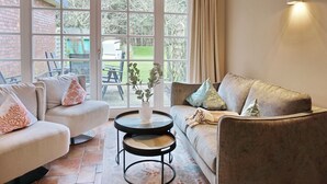 A living room with a sofa, armchair, and a small table with a vase.