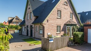 Ein zweistöckiges Haus mit steilem Dach, Ziegelaußenwand und einem Eingangstor aus Holz.