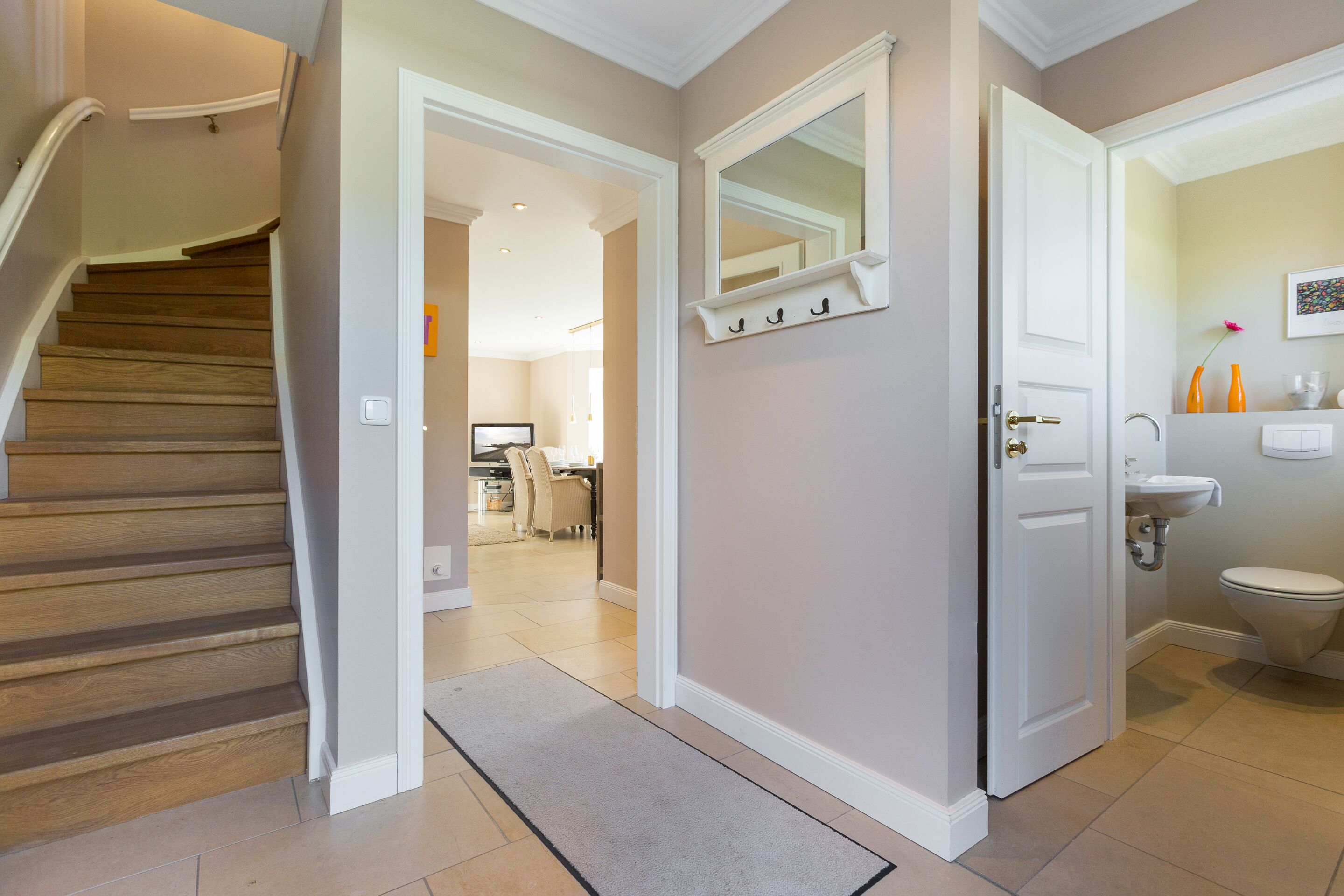 A staircase leading to a hallway with a kitchen in the background.