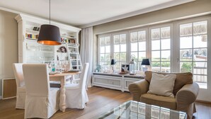 A dining area with a table set for four, a glass coffee table, and a sofa. - The most beautiful views! (Wenningstedt-Braderup (Sylt))