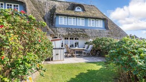 A thatched-roof house with a garden and outdoor seating area. - The most beautiful views! (Wenningstedt-Braderup (Sylt))