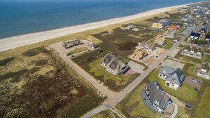 Vista aérea de un pueblo costero con casas, una playa y una zona de dunas.