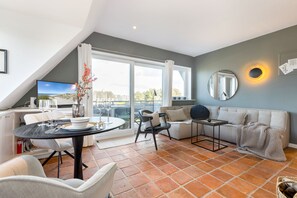 Una sala de estar moderna con comedor, ventanas amplias y un sofá acogedor.