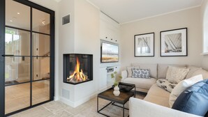 Ein modernes Wohnzimmer mit Kamin, einer Couch, einem Couchtisch und gerahmten Bildern an der Wand.