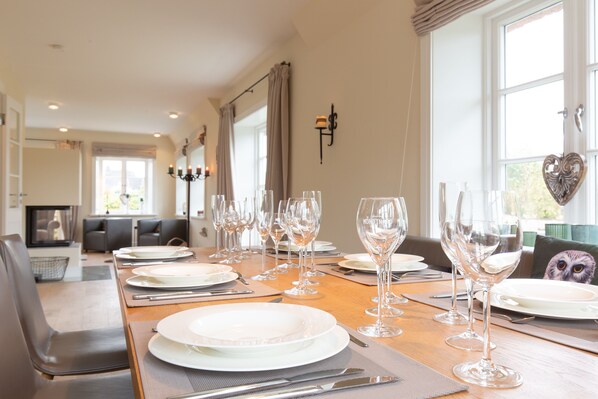Enjoy a formal dining experience in this elegantly set room, featuring a long table and comfortable seating area.